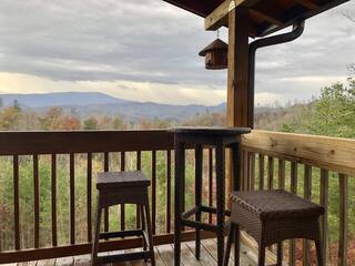 Deck with two bar height chairs and table looking out to mountains
