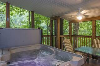 Hot tub on screened porch with table for 6 guests and ceiling fans