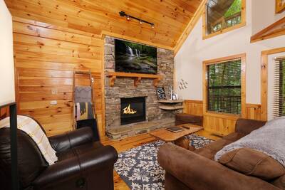 Treeside living room with stone encased seasonal gas fireplace