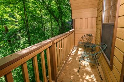 Treeside upper level covered back deck with table and chairs