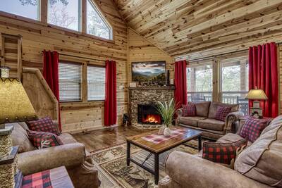 A Mountain Hideaway Lodge - Living room with seasonal stone encased wood burning fireplace