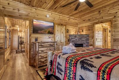 Cozy Cub Cabin main level bedroom with stone encased gas fireplace