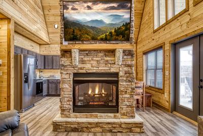 View to a Thrill double sided stone encased gas fireplace and 58 inch TV