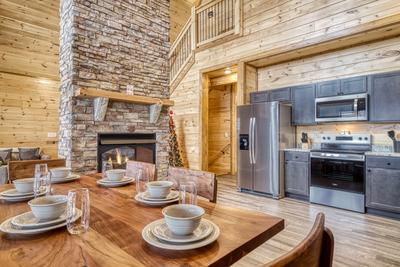 View to a Thrill dining area, fully furnished kitchen, and double sided stone encased gas fireplace