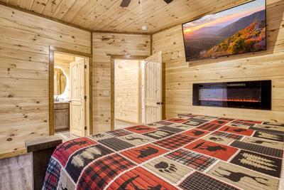 View to a Thrill main level bedroom with king bed, 58 inch TV, year round electric fireplace, and private bath