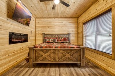 View to a Thrill main level bedroom with king bed, year round electric fireplace, and a 58 inch TV