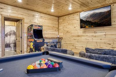 View to a Thrill lower level game room with pool table, arcade game, and 75 inch TV