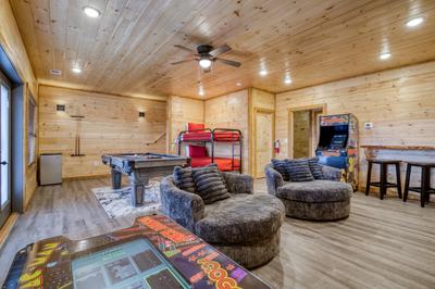 View to a Thrill lower level game room with two arcade games, pool table, and bunk beds