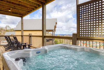 View to a Thrill lower level deck with a hot tub with mountain views