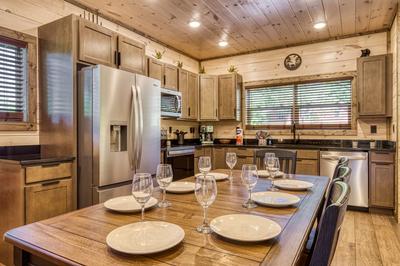 Honey Bear dining table and fully furnished kitchen with stainless steel appliances and granite countertops