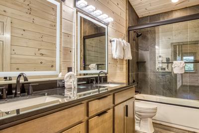 Honey Bear upper level bathroom with a double vanity with heated mirrors and a tub/shower combo