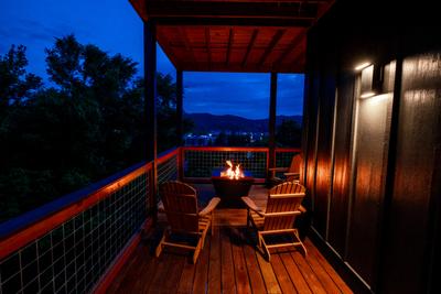 Honey Bear main level wrap around deck with propane fire pit and view of Pigeon Forge at night
