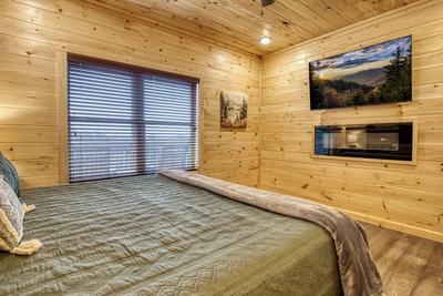 In The Clouds main level bedroom with king size bed, electric fireplace, and 58 inch TV
