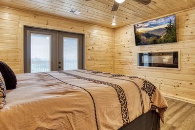 Upper level bedroom with king size bed, electric fireplace, and 58 inch TV