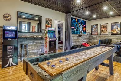 The Playful Bear lower level game room and theater with arcade games and shuffle board table