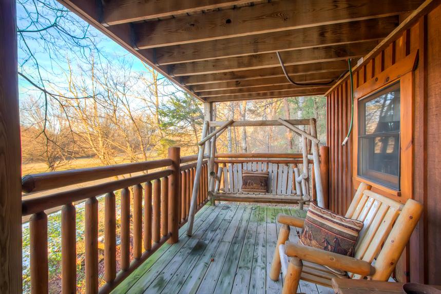 Enjoy the wooden porch swing and chairs on the porch of this 2 bedroom cabin in Pigeon Forge