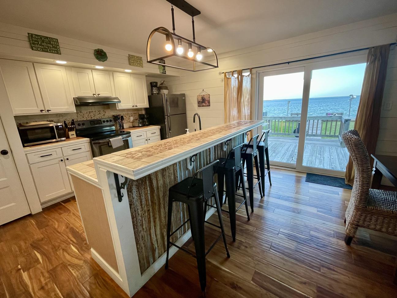 Galley kitchen with island seating and bay view in Rockport vacation rental