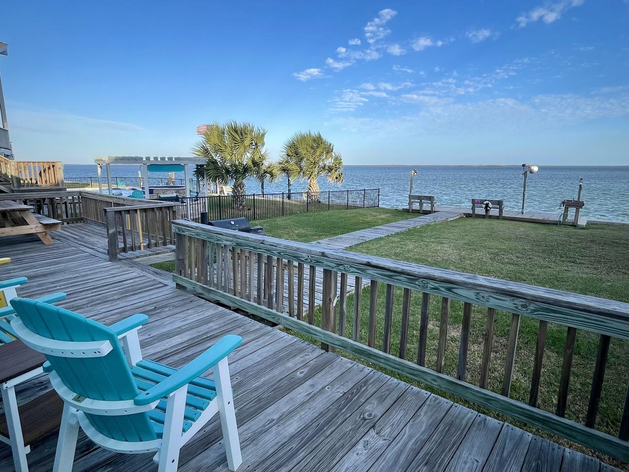 Waterfront deck with seating overlooking yard and fishing pier in Rockport Texas