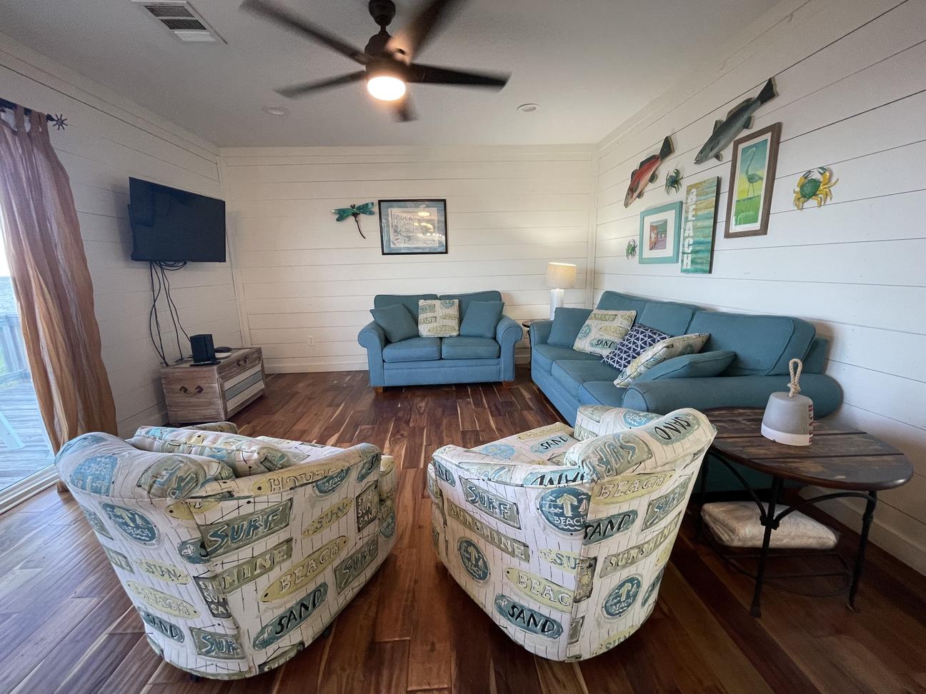 Coastal living room with blue sofas, accent chairs, and smart TV in Rockport rental