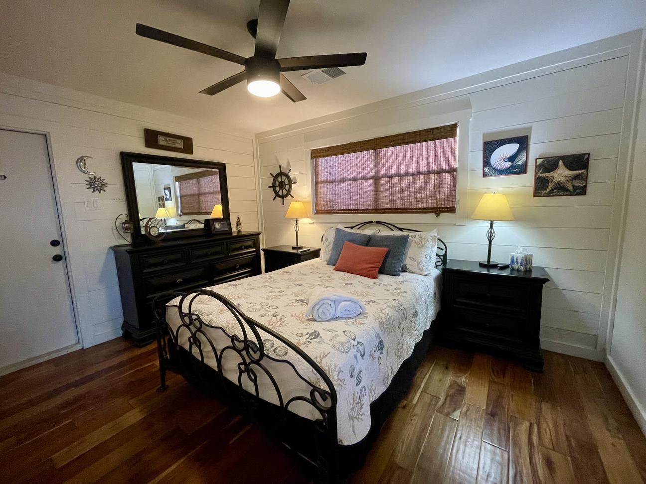 Master bedroom showing the queen size bed, a dresser, 2 nightstands and a ceiling fan