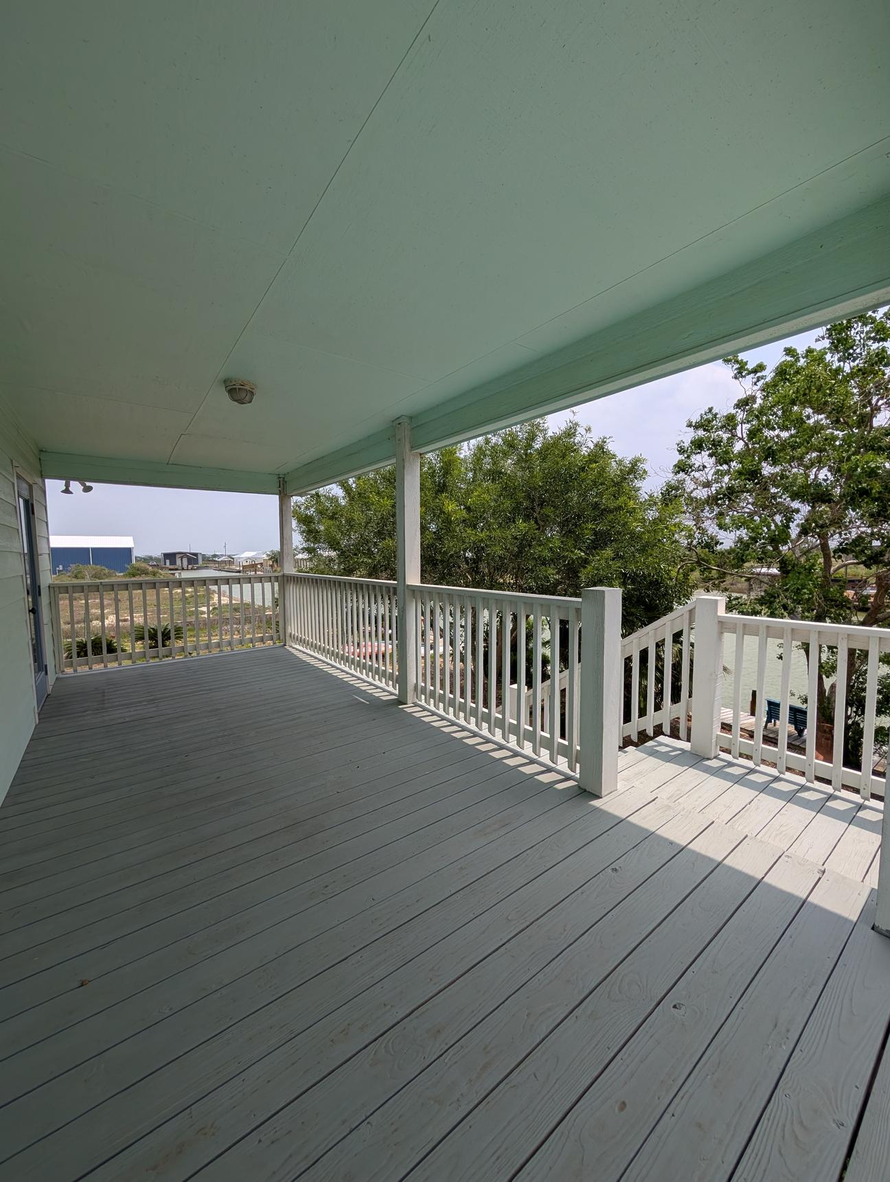 Wooden balcony with steps leading down to gardens and canal.