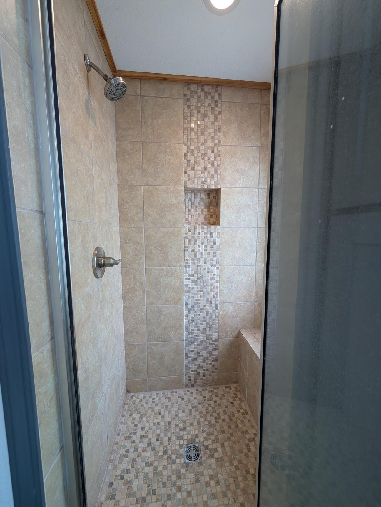 Tan tiled bathroom with walk in shower and soaking tub