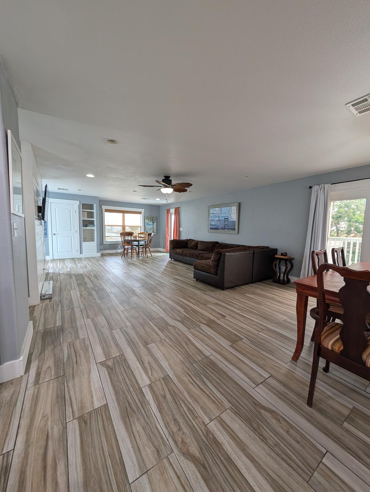 Open concept dining and living room with dining table, sectional couch and game table.
