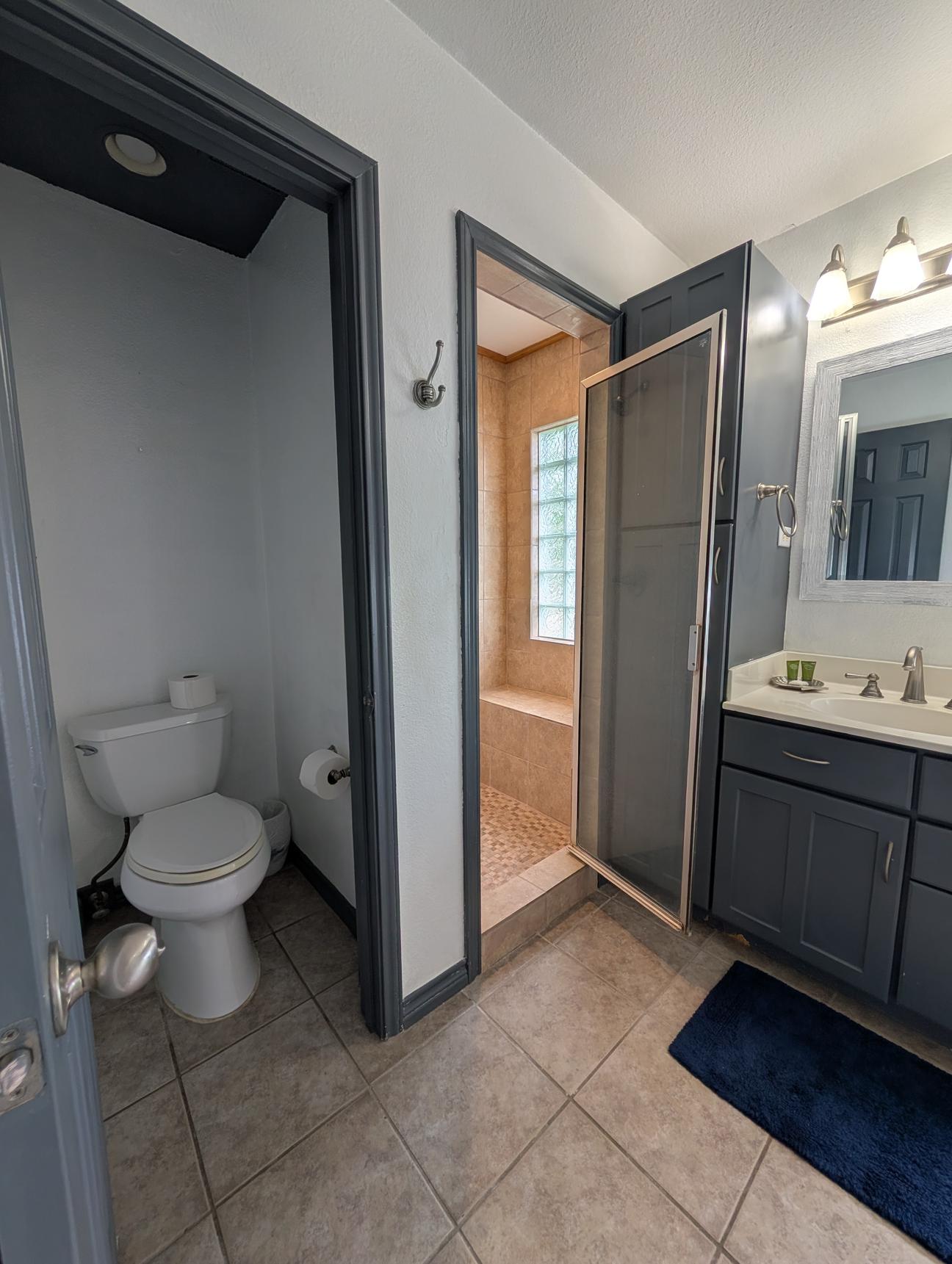 large, tan tiled bathroom with coastal decor