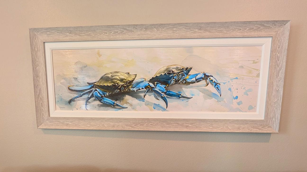 Wall art of two blue crabs on a tan wall