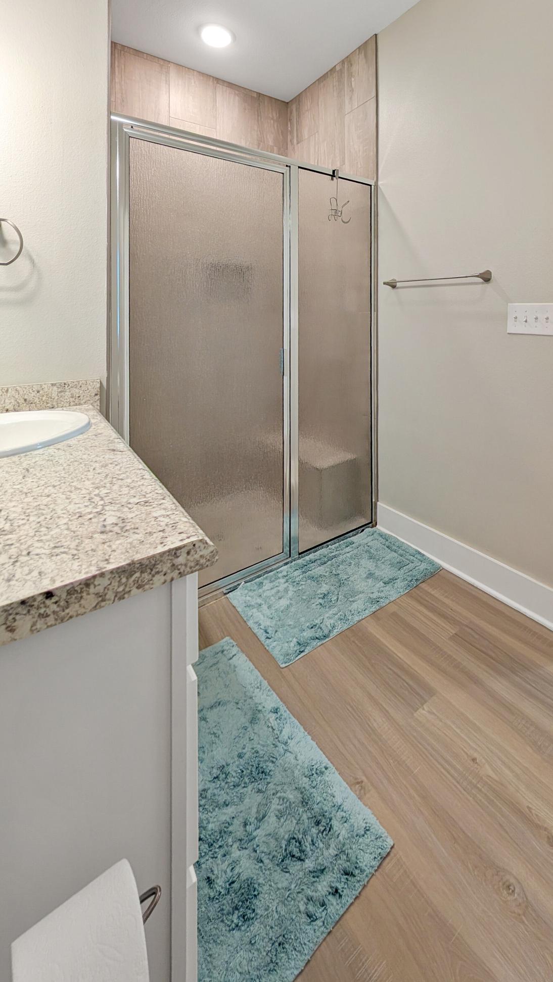 Walk in shower with glass doors in a bathroom decorated in coastal themes. 