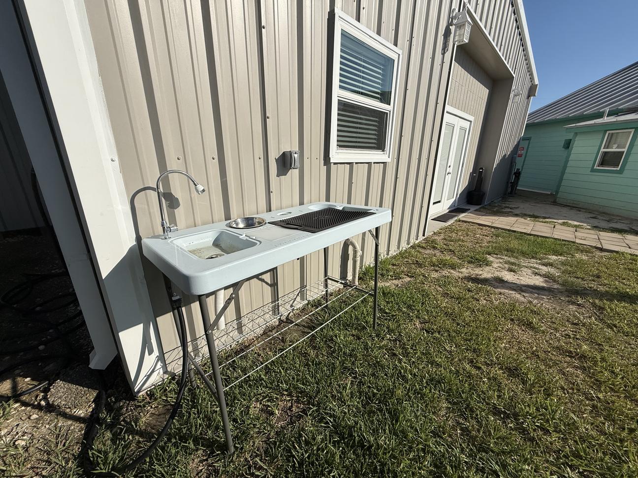Outdoor fish-cleaning station with sink and prep area beside a canal-front coastal property, designed for fishing and boating guests.