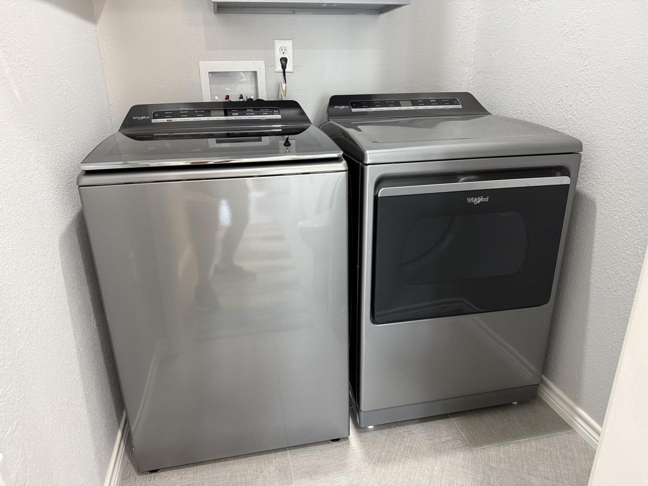 Full size silver washer and dryer in the laundry room. 