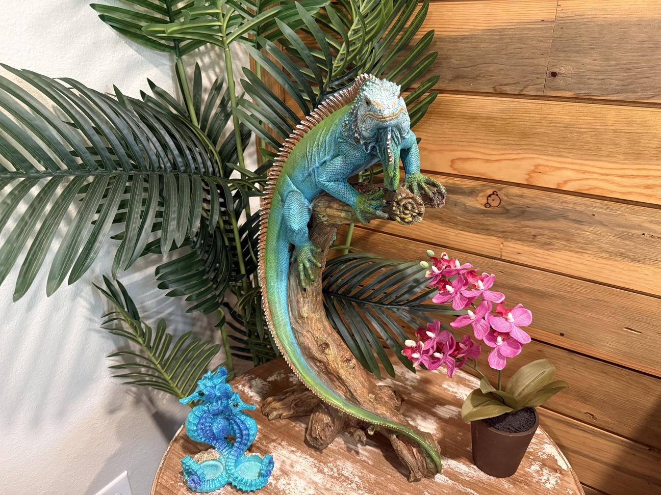 Tropical decor inthe living room includes a life sized colorful iguana on a fake plant.