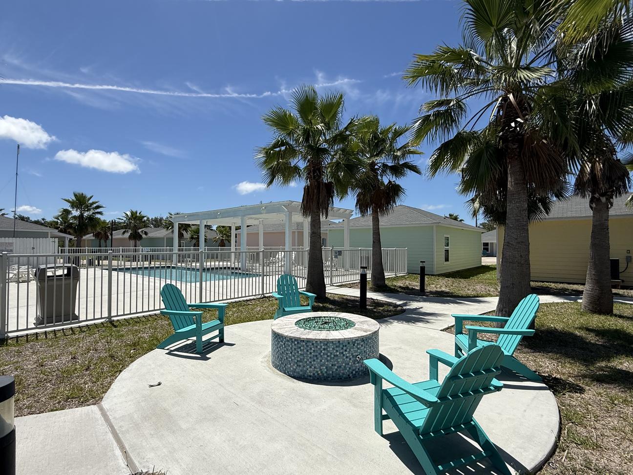 Community firepit and blue chairs are located next to the sparkling community pool.