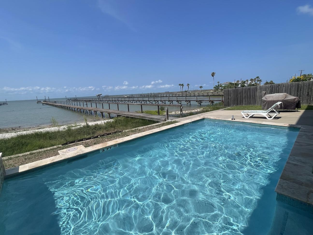 Waterfront swimming pool overlooking Copano Bay with a long wooden pier