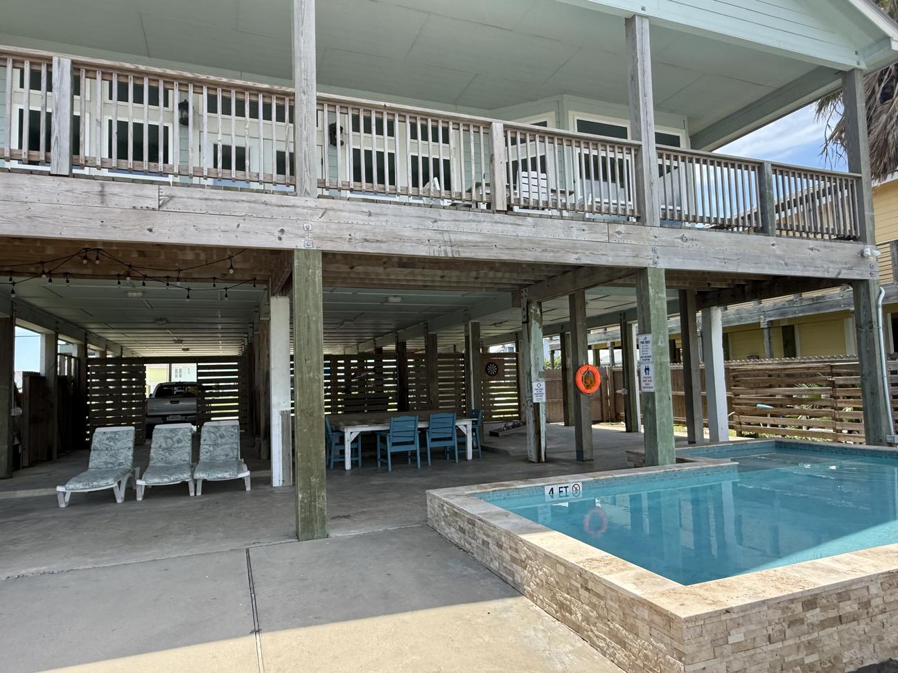 Covered patio with pool under a raised beach house deck