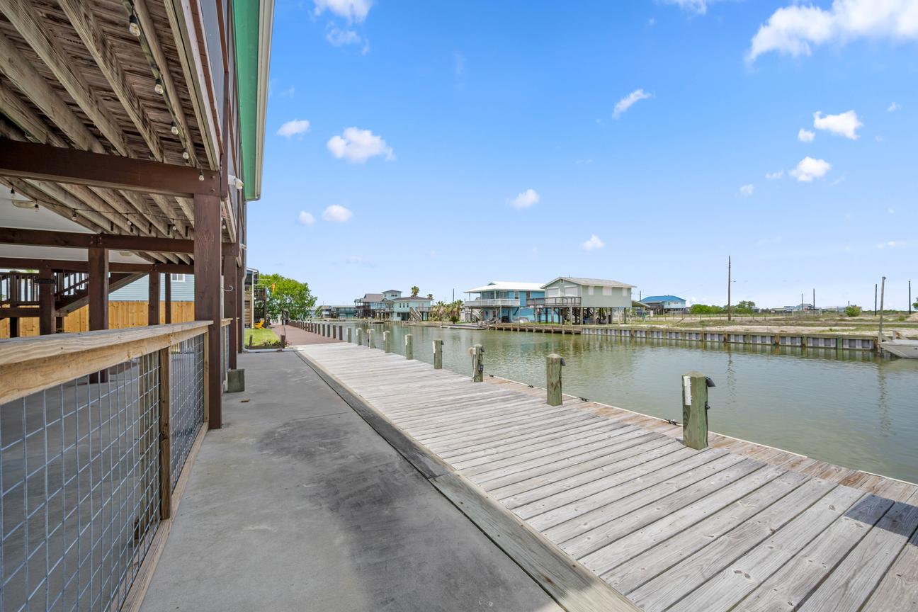 Private wooden fishing dock with boat tie-up posts along a calm coastal canal.