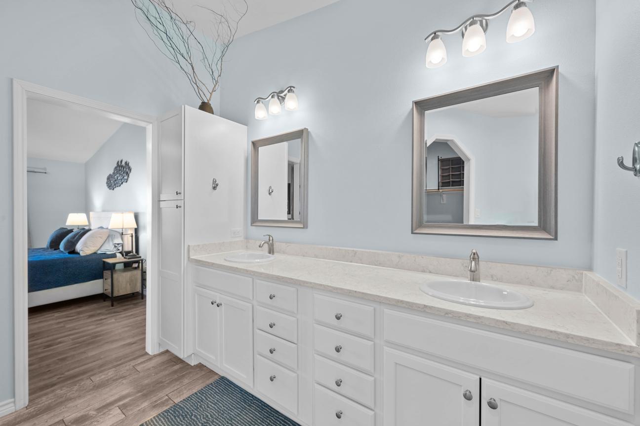 Primary bathroom with a long white double vanity, two sinks, framed mirrors, and coastal blue walls.