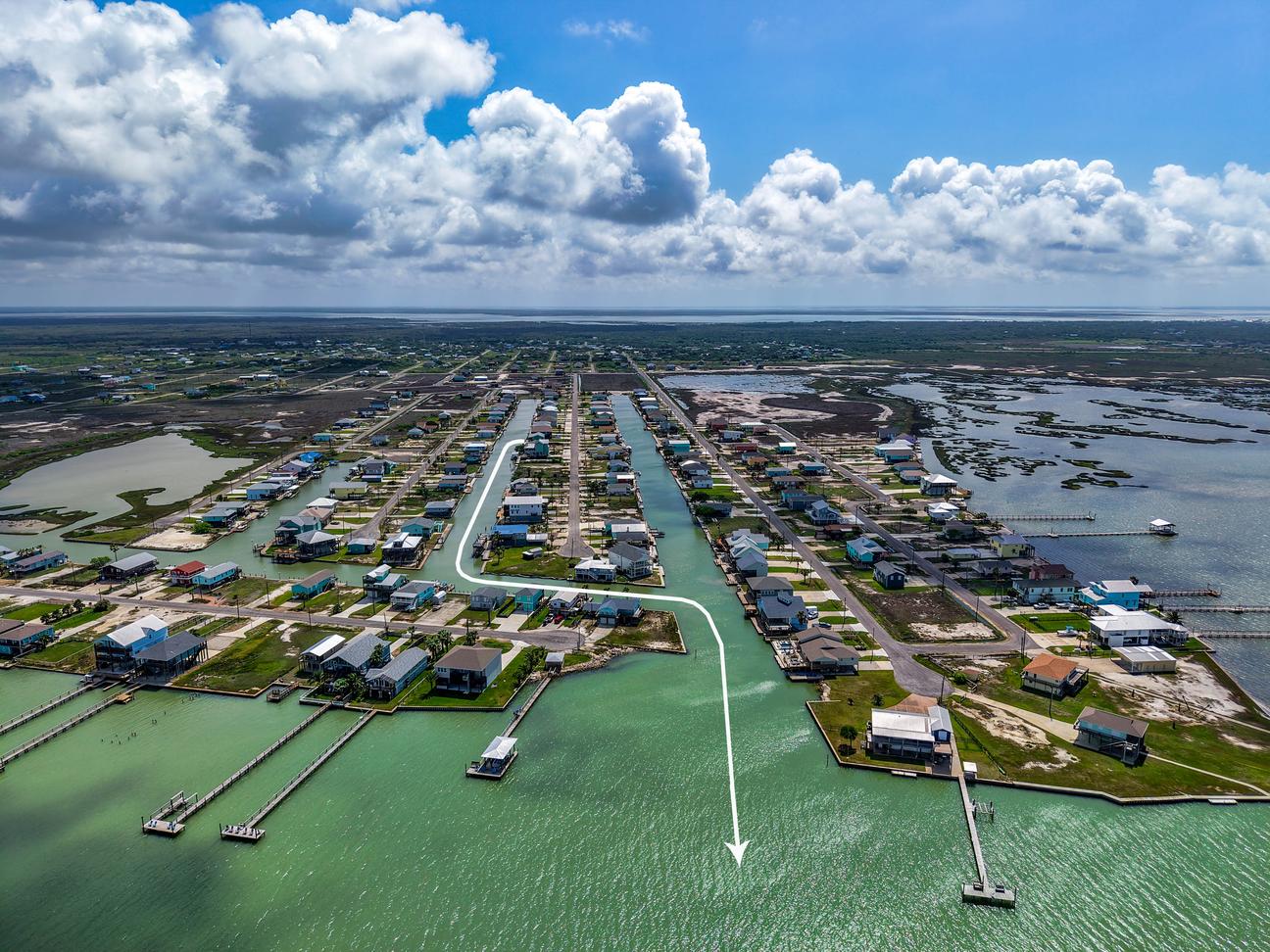 Aerial view of a canal neighborhood opening into Copano Bay, with a white line marking the boating rout