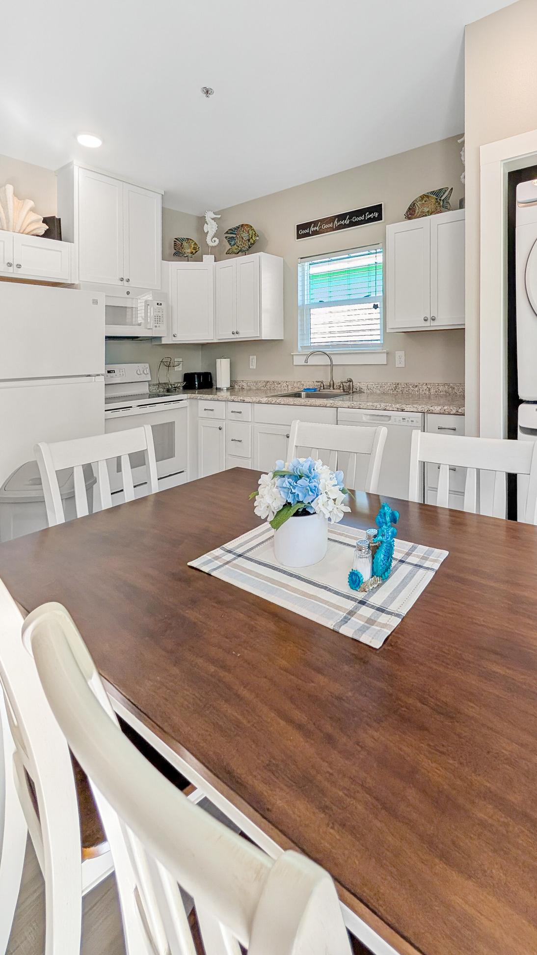 Wood and white dining table with seating for six people located in between the kitchen and the living room. 