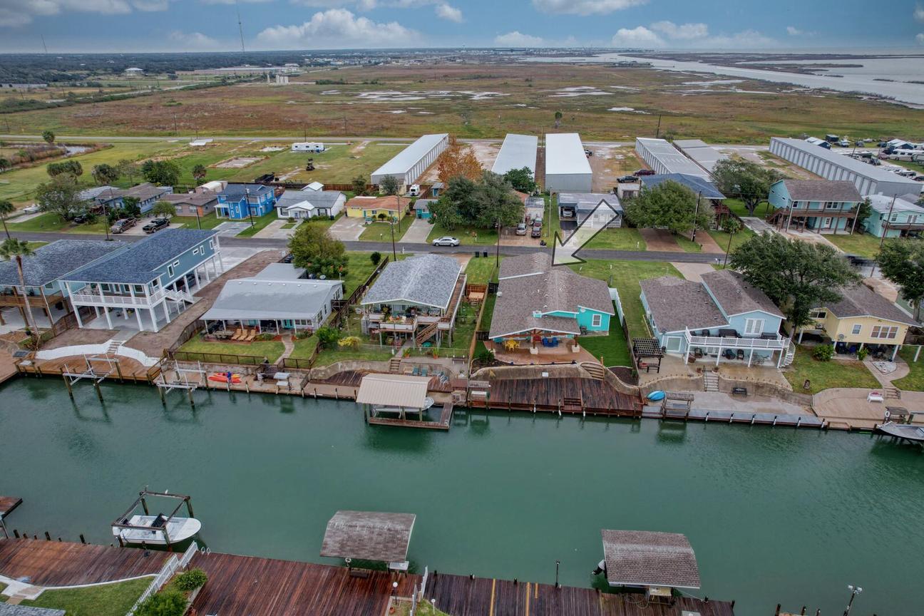 Aerial view of a row of homes with docks and covered dock structures along a canal, with Estes Flats in the distance.