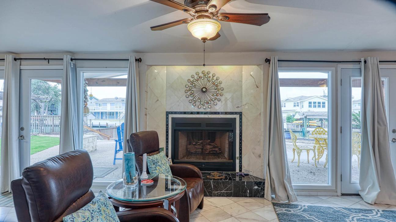 Two leather recliners in front of a tiled fireplace, with glass doors on both sides opening to the patio.