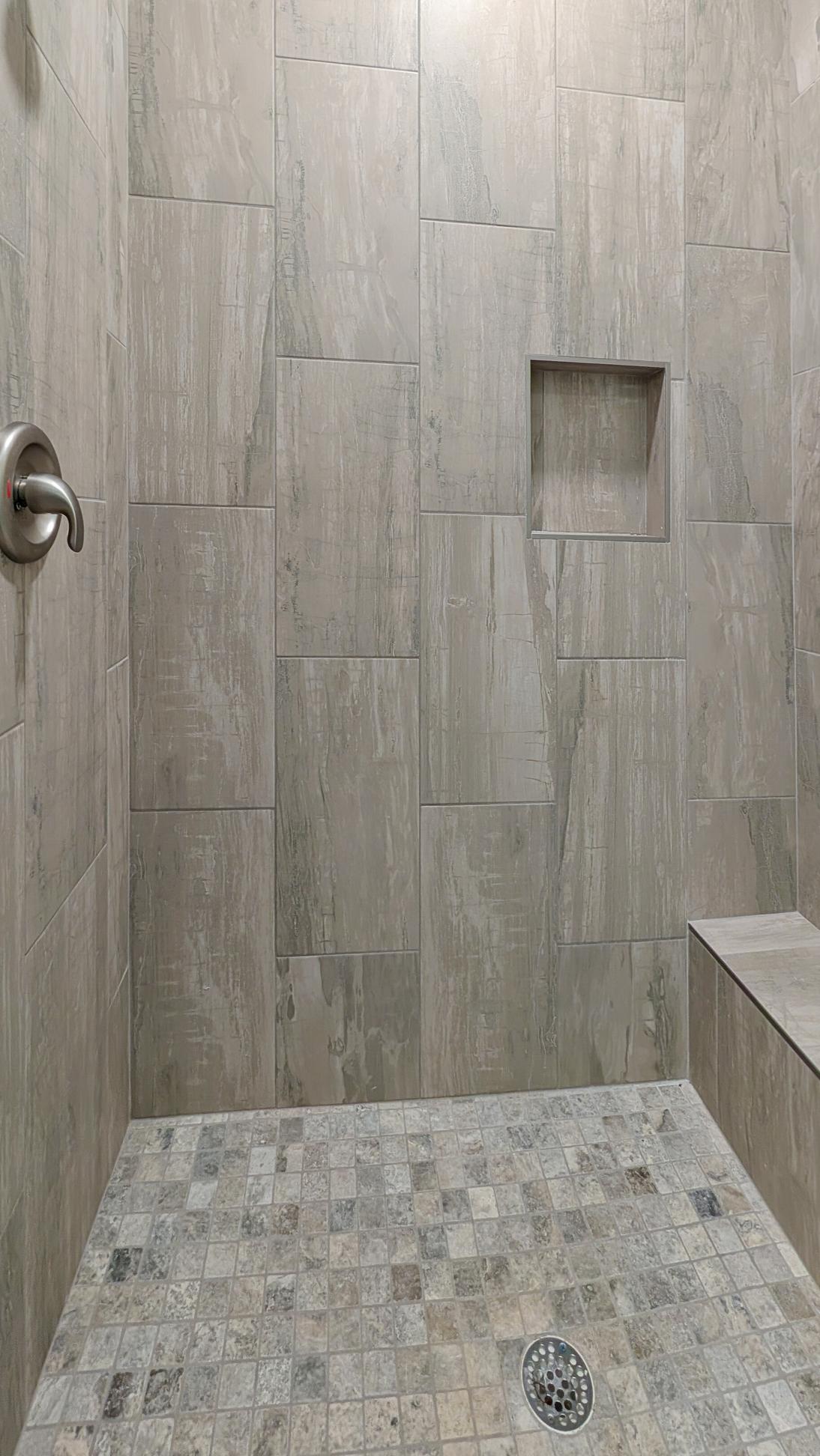 Walk-in shower with tan tile and a shower bench