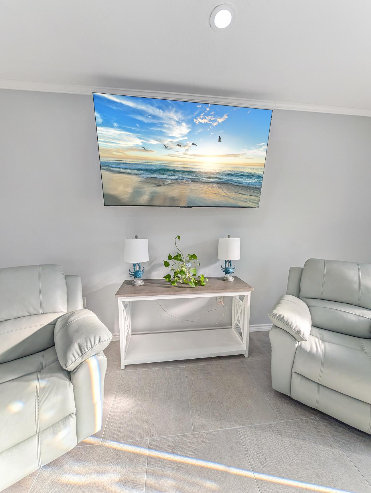 Large smart TV with two light blue leather recliners. 