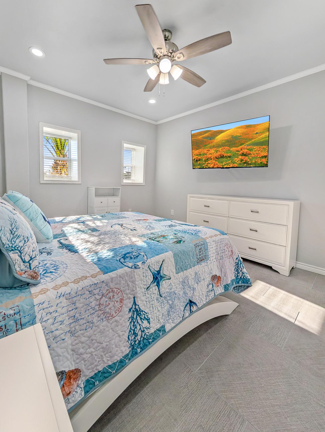 WHite queen bed with blue  coastal quilt.