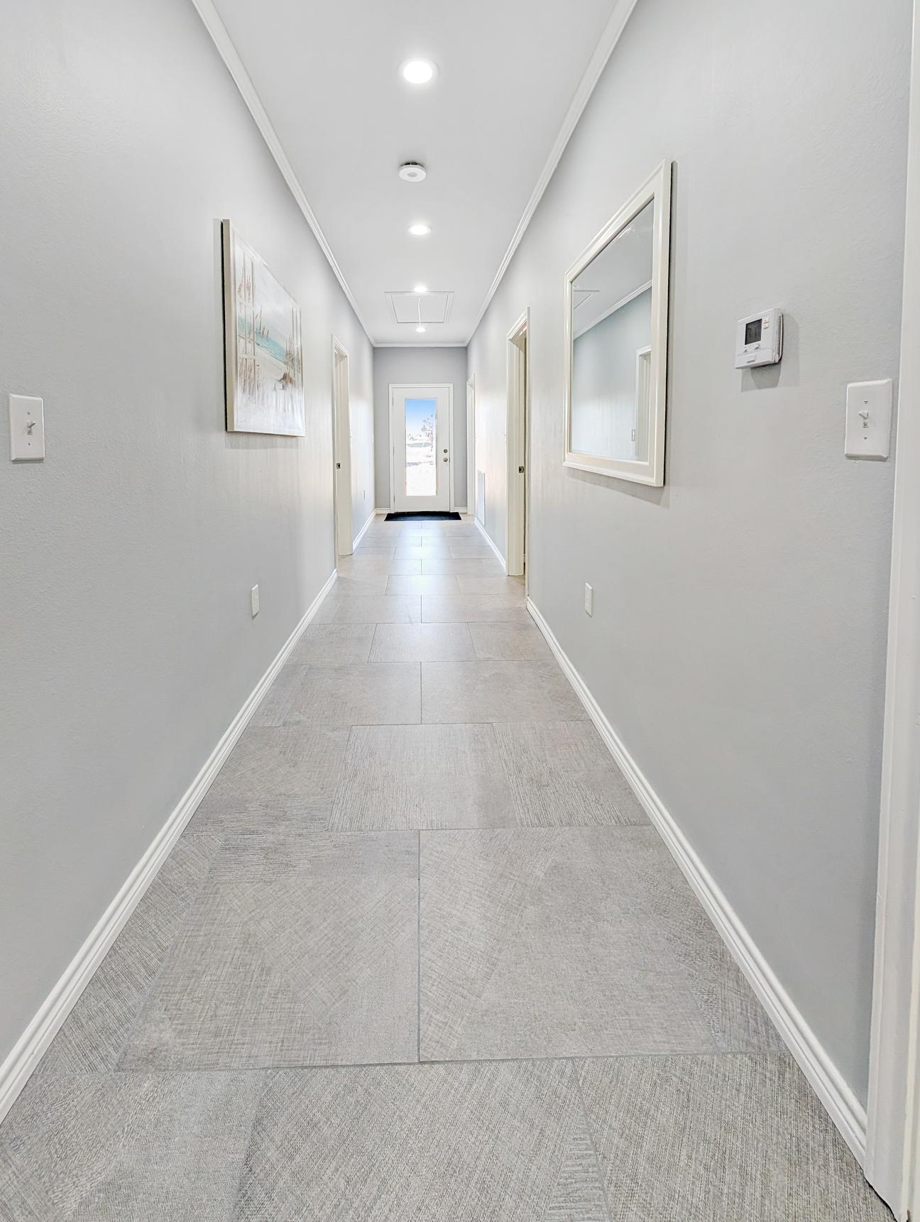 Long hallway with doorways to two bedrooms on each side.