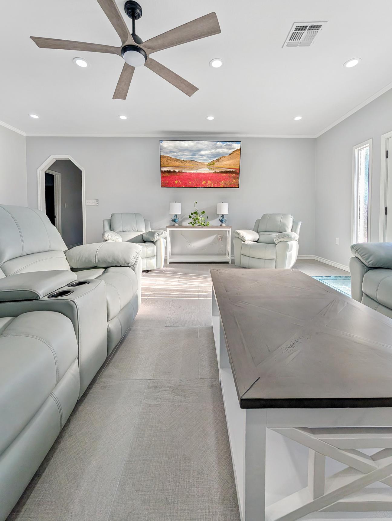 Coffee table, blue leather recliners, large smart tv.