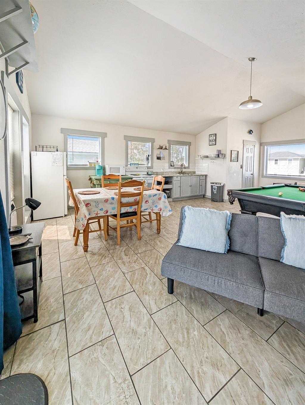 pool table, shelf with games, kitchen and couch