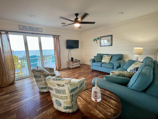 Cozy couches and chairs in the living room face large windows with bay views.