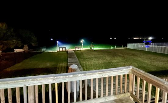 Waterfront yard and deck at night with illuminated fishing pier in Rockport Texas